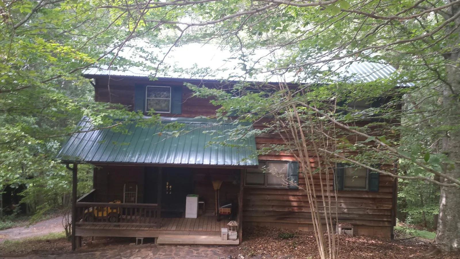 Green metal roof and covered porch on a log cabin in Vermillion