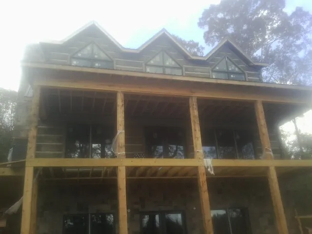 Dormers and porch framing on a large log home under construction — Roof Coating work by our crew in Vermillion