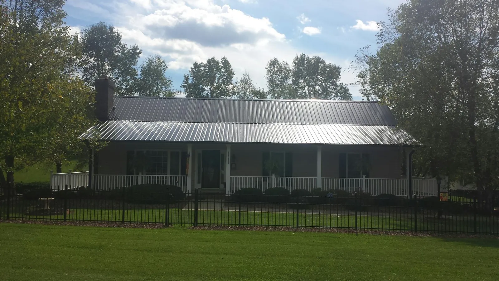 Gray metal roof on a brick ranch with a full width front porch — Gutter Guard Installation work by our crew in Vermillion
