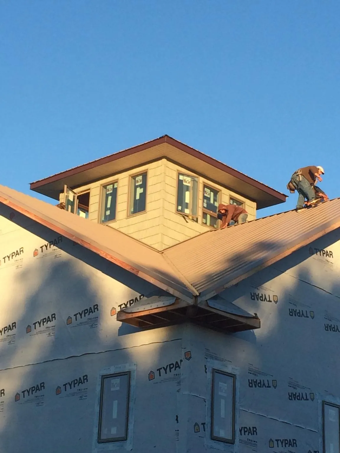 Roofers working around a rooftop cupola on a new metal roof at sunset — Roof Waterproofing in Vermillion by Roofing Brothers